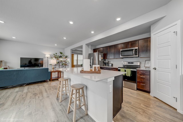 3640 S Clinton Rd, Spokane Valley, WA 99206 - kitchen with stainless steel appliances, a breakfast bar area, light wood-style floors, dark brown cabinets, and recessed lighting