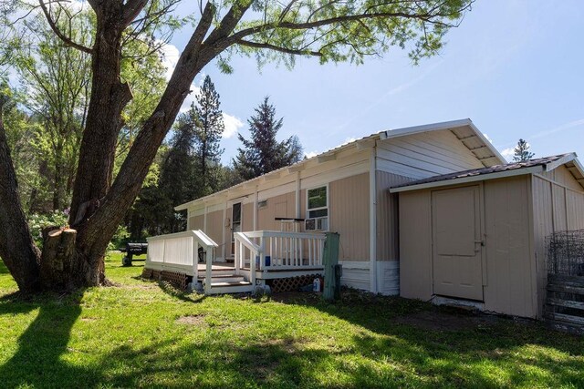 105 E Aspen Ave, Springdale, WA 99173 - rear view of house featuring a deck, a lawn, and a storage unit
