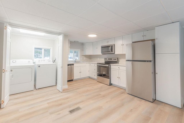 105 E Aspen Ave, Springdale, WA 99173 - kitchen featuring appliances with stainless steel finishes, washer and dryer, open shelves, a drop ceiling, and white cabinets