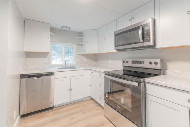 105 E Aspen Ave, Springdale, WA 99173 - kitchen with stainless steel appliances, open shelves, white cabinetry, light wood-style flooring, and a paneled ceiling