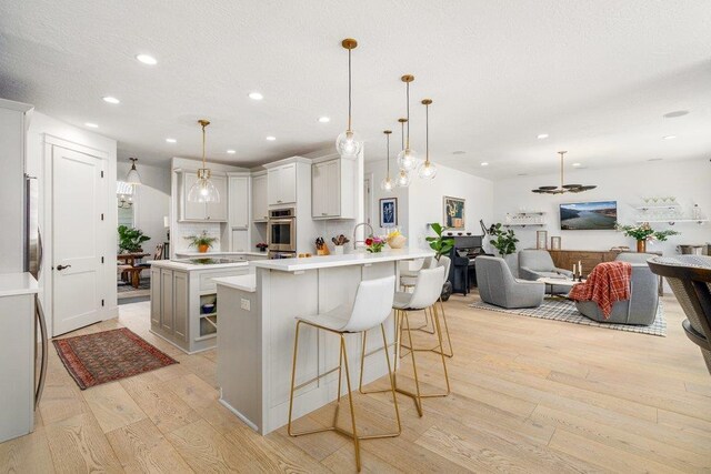 3742 W Cielo View Ct, Coeur D Alene, ID 83814 - kitchen with stainless steel oven, light wood-style flooring, recessed lighting, a peninsula, and a kitchen bar