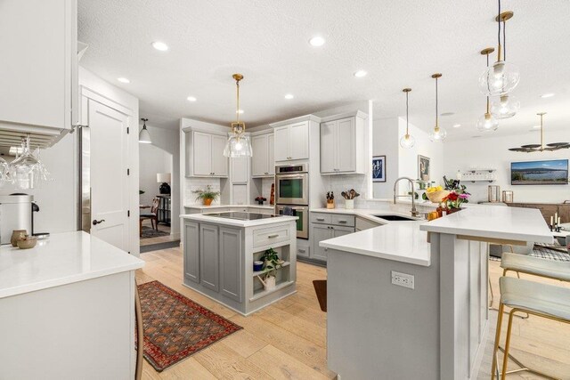 3742 W Cielo View Ct, Coeur D Alene, ID 83814 - kitchen featuring gray cabinets, a peninsula, a breakfast bar area, light wood-type flooring, and recessed lighting