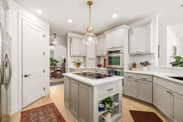 3742 W Cielo View Ct, Coeur D Alene, ID 83814 - kitchen with appliances with stainless steel finishes, gray cabinetry, tasteful backsplash, a center island, and light wood-style flooring