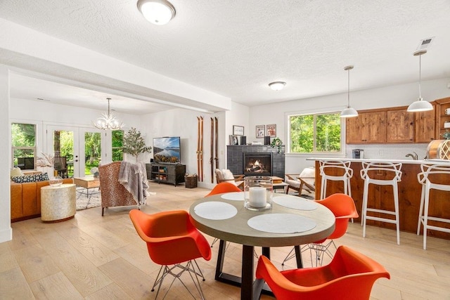 3742 W Cielo View Ct, Coeur D Alene, ID 83814 - dining space featuring light wood-style floors, a brick fireplace, a textured ceiling, and french doors