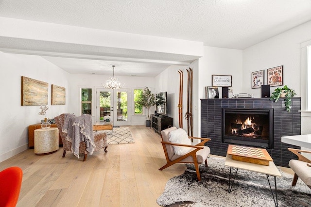 3742 W Cielo View Ct, Coeur D Alene, ID 83814 - living room with light wood-style flooring, a tile fireplace, a chandelier, and french doors