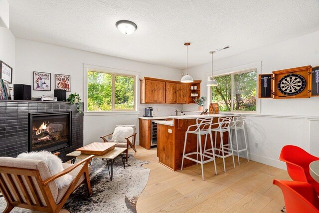 3742 W Cielo View Ct, Coeur D Alene, ID 83814 - kitchen with brown cabinetry, beverage cooler, plenty of natural light, a breakfast bar, and a textured ceiling