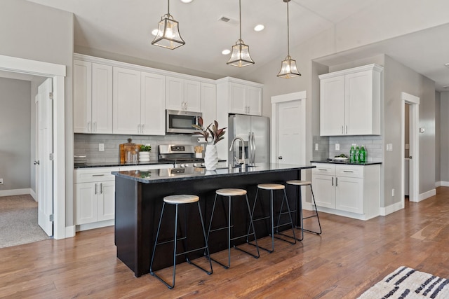 20219 E 11th Ave Unit 20219E 11Th, Greenacres, WA 99016 - kitchen featuring appliances with stainless steel finishes, dark countertops, tasteful backsplash, a kitchen breakfast bar, and white cabinets
