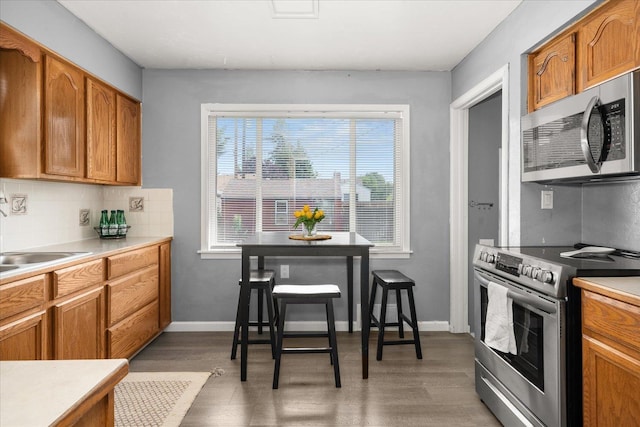 3623 W Longfellow Ave, Spokane, WA 99205 - kitchen with stainless steel appliances, wood finished floors, tasteful backsplash, light countertops, and brown cabinetry