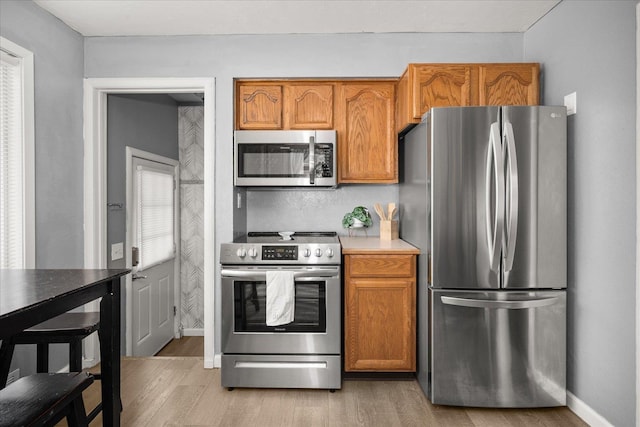 3623 W Longfellow Ave, Spokane, WA 99205 - kitchen with stainless steel appliances, light wood finished floors, brown cabinetry, and light countertops