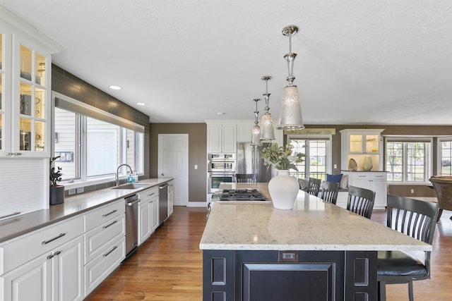 2804 W Johannsen Rd, Spokane, WA 99208 - kitchen with stainless steel appliances, a center island, white cabinetry, a kitchen bar, and wood finished floors