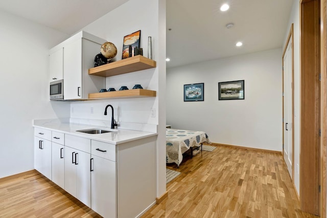 2435 W Riverside Ave, Spokane, WA 99201 - kitchen with open shelves, stainless steel microwave, light wood-type flooring, recessed lighting, and white cabinets