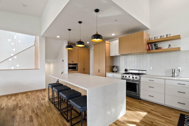 2435 W Riverside Ave, Spokane, WA 99201 - kitchen with stainless steel appliances, light wood-style floors, tasteful backsplash, a kitchen island, and recessed lighting