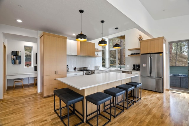 2435 W Riverside Ave, Spokane, WA 99201 - kitchen featuring appliances with stainless steel finishes, open shelves, light wood-type flooring, a breakfast bar, and recessed lighting