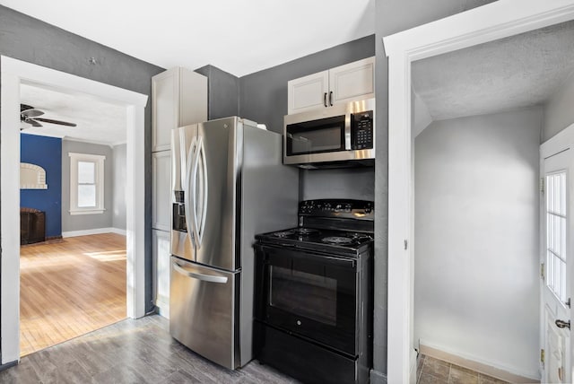 107 E 29th Ave, Spokane, WA 99203 - kitchen with appliances with stainless steel finishes, a fireplace, a ceiling fan, wood finished floors, and white cabinets
