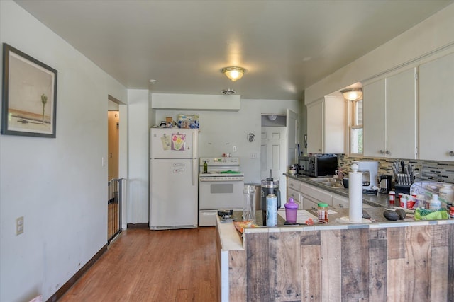 2804 E Marshall Ave, Spokane, WA 99207 - kitchen featuring white appliances, light wood-style flooring, white cabinets, a peninsula, and backsplash