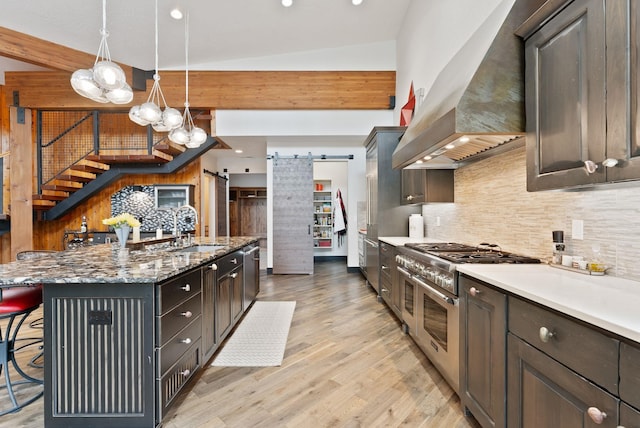 25204 N Lords Ln, Chattaroy, WA 99003 - kitchen featuring appliances with stainless steel finishes, wall chimney exhaust hood, a barn door, decorative backsplash, and a breakfast bar area