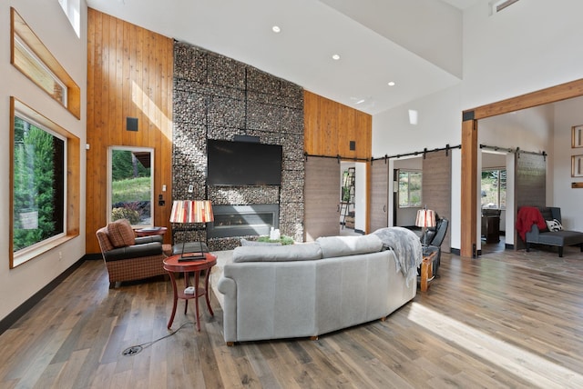 25204 N Lords Ln, Chattaroy, WA 99003 - living area with a barn door, high vaulted ceiling, wood finished floors, recessed lighting, and wooden walls