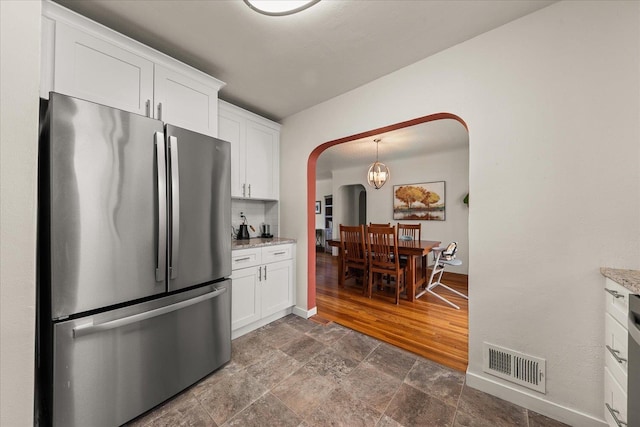 2338 W Euclid Ave, Spokane, WA 99205 - kitchen with freestanding refrigerator, arched walkways, white cabinetry, and dark stone finish floors