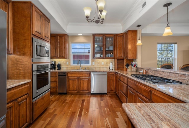 1828 W Riverside Ave Unit 301, Spokane, WA 99201 - kitchen with stainless steel appliances, a raised ceiling, hardwood / wood-style flooring, brown cabinets, and crown molding