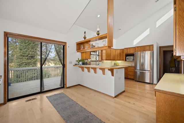 21407 W Baker Rd, Cheney, WA 99004 - kitchen with stainless steel appliances, a peninsula, open shelves, brown cabinetry, and high vaulted ceiling