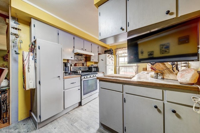 203 N Mcdonald Rd, Spokane, WA 99216 - kitchen featuring stainless steel range with gas cooktop, freestanding refrigerator, light wood-type flooring, under cabinet range hood, and light countertops
