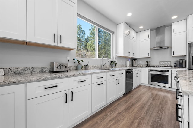 11625 N Alberta Ln, Spokane, WA 99218 - kitchen featuring appliances with stainless steel finishes, wall chimney range hood, wood finished floors, white cabinets, and light stone counters