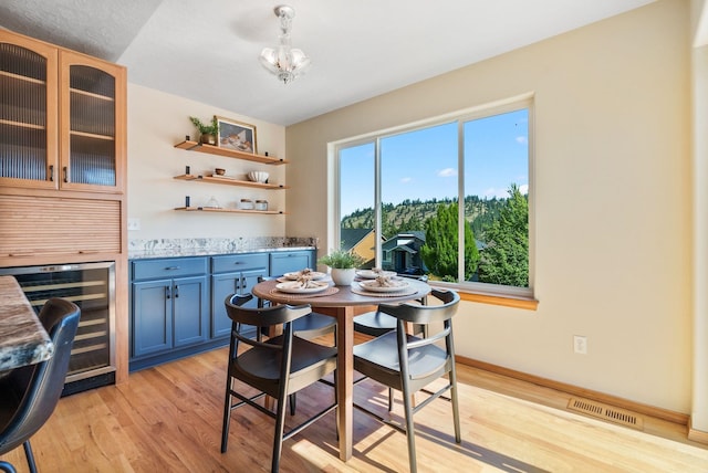 711 W Bolan Ave, Spokane, WA 99224 - dining room with beverage cooler, a bar, light wood finished floors, and a chandelier