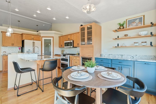 711 W Bolan Ave, Spokane, WA 99224 - kitchen with white appliances, lofted ceiling, a kitchen island with sink, decorative backsplash, and light wood-type flooring
