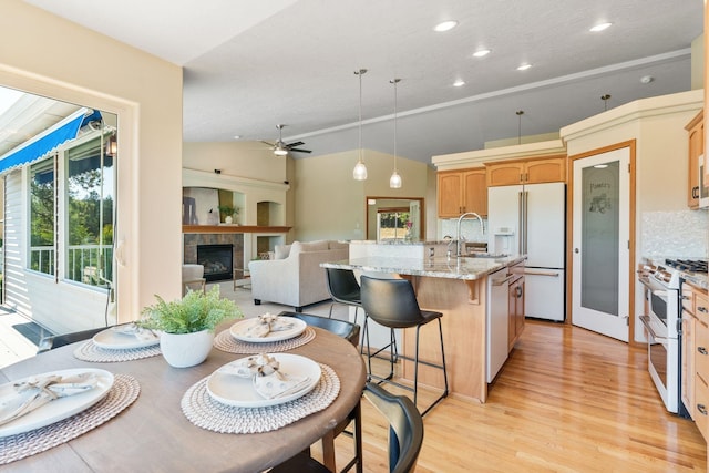 711 W Bolan Ave, Spokane, WA 99224 - kitchen with white appliances, a ceiling fan, light wood-style floors, a fireplace, and a kitchen breakfast bar