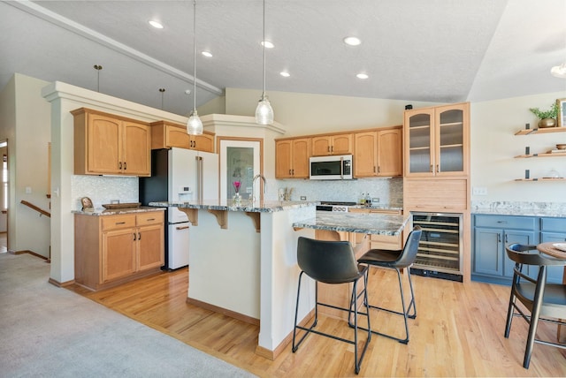 711 W Bolan Ave, Spokane, WA 99224 - kitchen with beverage cooler, stainless steel microwave, white fridge with ice dispenser, a breakfast bar, and vaulted ceiling