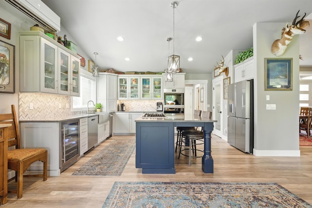 5159 W Village Blvd, Rathdrum, ID 83858 - kitchen featuring wine cooler, appliances with stainless steel finishes, decorative backsplash, a breakfast bar area, and a center island