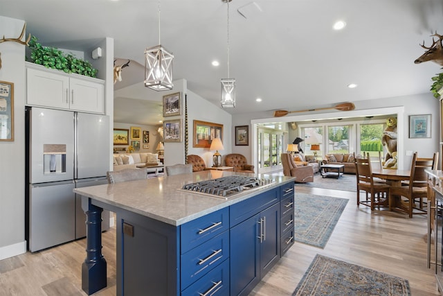 5159 W Village Blvd, Rathdrum, ID 83858 - kitchen with appliances with stainless steel finishes, open floor plan, white cabinets, vaulted ceiling, and blue cabinets