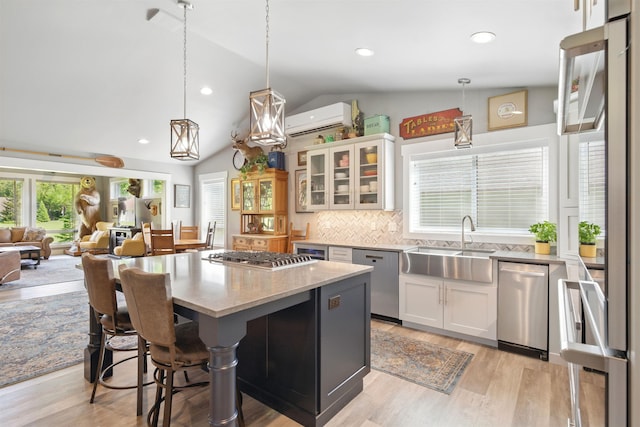 5159 W Village Blvd, Rathdrum, ID 83858 - kitchen featuring stainless steel appliances, a wall mounted AC, vaulted ceiling, white cabinets, and glass insert cabinets