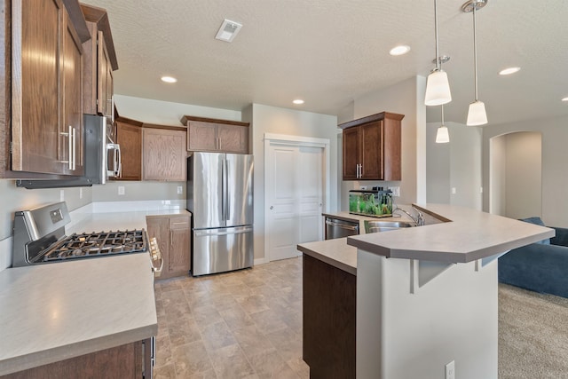 1101 S Pillar Rock Dr, Spokane, WA 99224 - kitchen with appliances with stainless steel finishes, arched walkways, a peninsula, a breakfast bar area, and pendant lighting