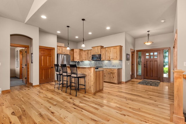 9510 N Doak Rd, Spokane, WA 99217 - kitchen featuring appliances with stainless steel finishes, light wood-type flooring, a kitchen breakfast bar, decorative backsplash, and recessed lighting