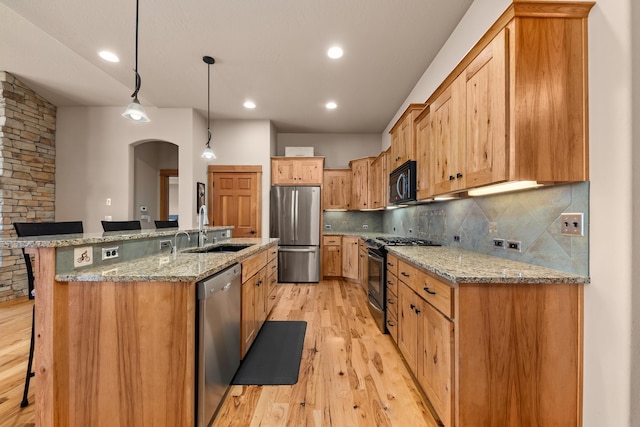 9510 N Doak Rd, Spokane, WA 99217 - kitchen with appliances with stainless steel finishes, light wood-style flooring, backsplash, a kitchen breakfast bar, and arched walkways