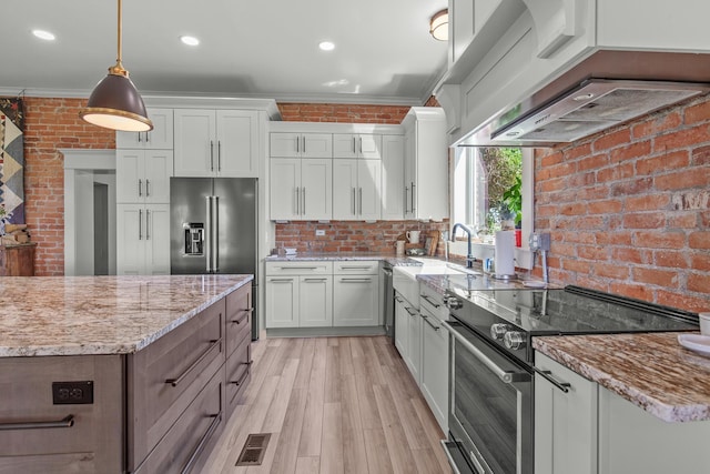 28752 Tramm Rd, Reardan, WA 99029 - kitchen with stainless steel appliances, ornamental molding, brick wall, light wood-style flooring, and light stone counters