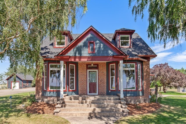 28752 Tramm Rd, Reardan, WA 99029 - view of front of house with a porch, a front lawn, a shingled roof, and brick siding