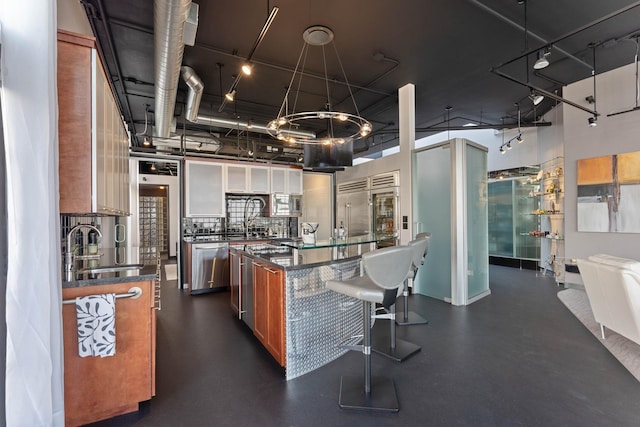 2230 W Riverside Ave # 302, Spokane, WA 99201 - kitchen with a kitchen island, a breakfast bar area, built in appliances, decorative backsplash, and a towering ceiling