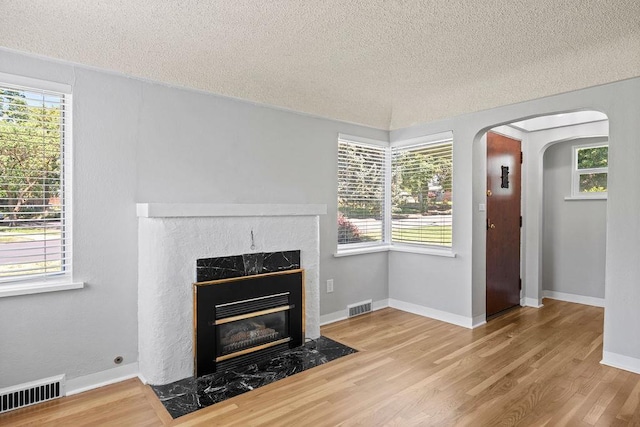 3307 W Euclid Ave, Spokane, WA 99205 - unfurnished living room featuring a textured ceiling, wood finished floors, a fireplace, arched walkways, and healthy amount of natural light