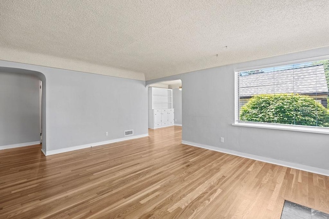 3307 W Euclid Ave, Spokane, WA 99205 - unfurnished room with arched walkways, a textured ceiling, and wood finished floors