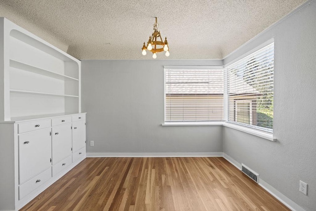 3307 W Euclid Ave, Spokane, WA 99205 - unfurnished dining area featuring a textured ceiling, a chandelier, and wood finished floors