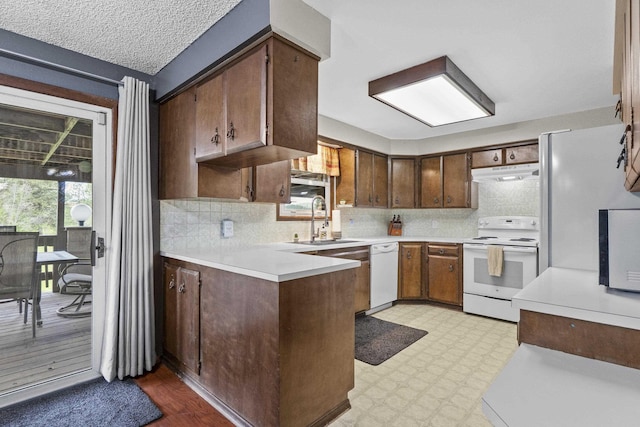 15906 N Forker Rd, Spokane, WA 99217 - kitchen with white appliances, light countertops, a peninsula, under cabinet range hood, and backsplash