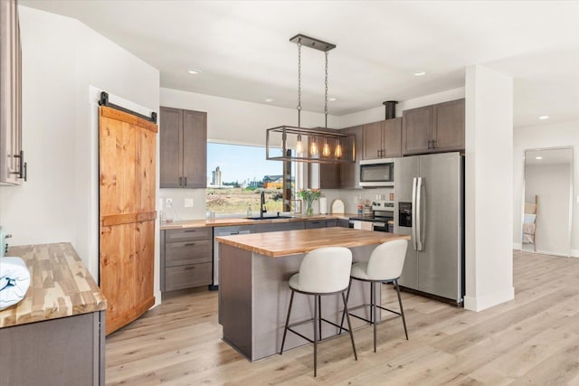 25751 Westfield Ln, Davenport, WA 99122 - kitchen with stainless steel appliances, wooden counters, a breakfast bar area, light wood-style flooring, and a kitchen island