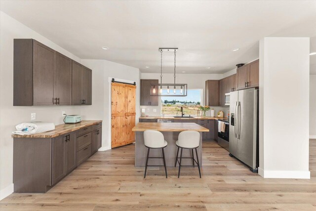 25751 Westfield Ln, Davenport, WA 99122 - kitchen featuring appliances with stainless steel finishes, a kitchen breakfast bar, butcher block countertops, a kitchen island, and light wood finished floors