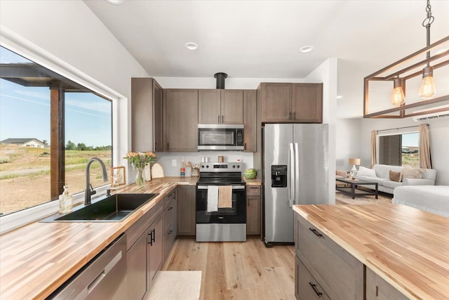 25751 Westfield Ln, Davenport, WA 99122 - kitchen featuring stainless steel appliances, butcher block countertops, light wood-type flooring, hanging light fixtures, and open floor plan