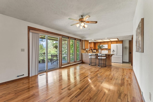 3827 E Funk Ave, Spokane, WA 99223 - unfurnished living room with vaulted ceiling, light wood finished floors, a ceiling fan, and a textured ceiling