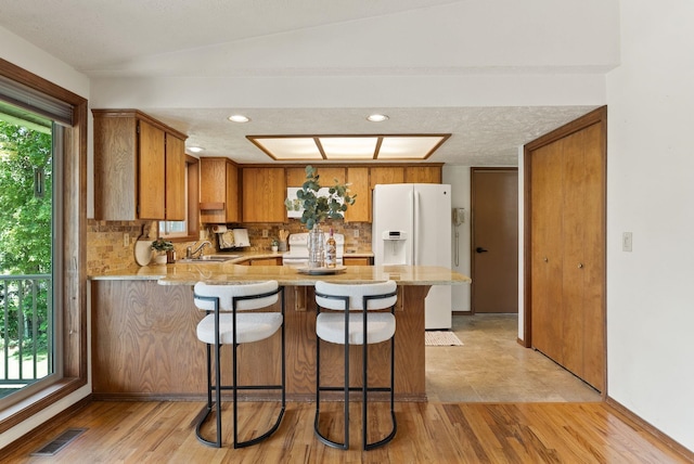 3827 E Funk Ave, Spokane, WA 99223 - kitchen with a peninsula, white appliances, brown cabinetry, tasteful backsplash, and light wood finished floors