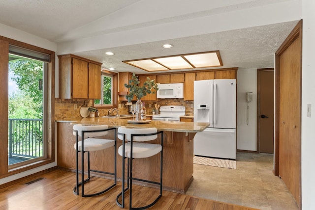 3827 E Funk Ave, Spokane, WA 99223 - kitchen featuring white appliances, a peninsula, backsplash, brown cabinets, and light countertops