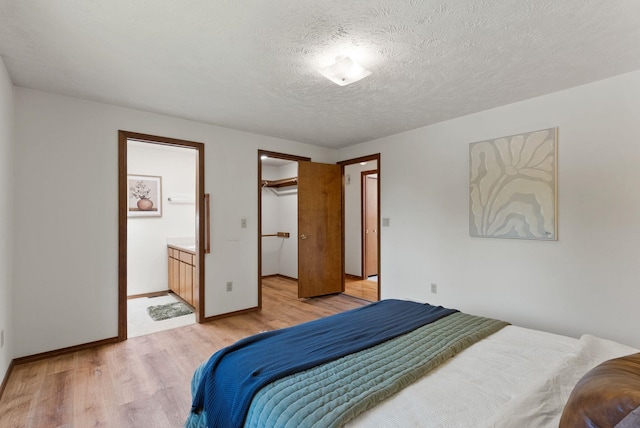 3827 E Funk Ave, Spokane, WA 99223 - bedroom with light wood-style floors, ensuite bathroom, a textured ceiling, and a walk in closet
